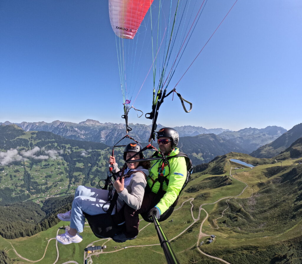 zwei Personen im Tandem am Fliegen über den Bergen